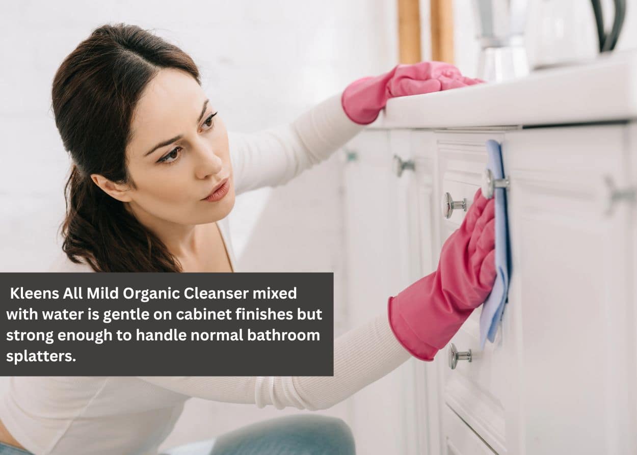 Homeowner cleaning bathroom cabinet doors and hardware as part of regular cabinet maintenance. Caption: Kleens All Mild Organic Cleanser mixed with water is gentle on cabinet finishes but strong enough to handle normal bathroom splatters.